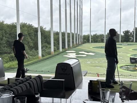Team members hitting golf balls in the driving bays at Topgolf