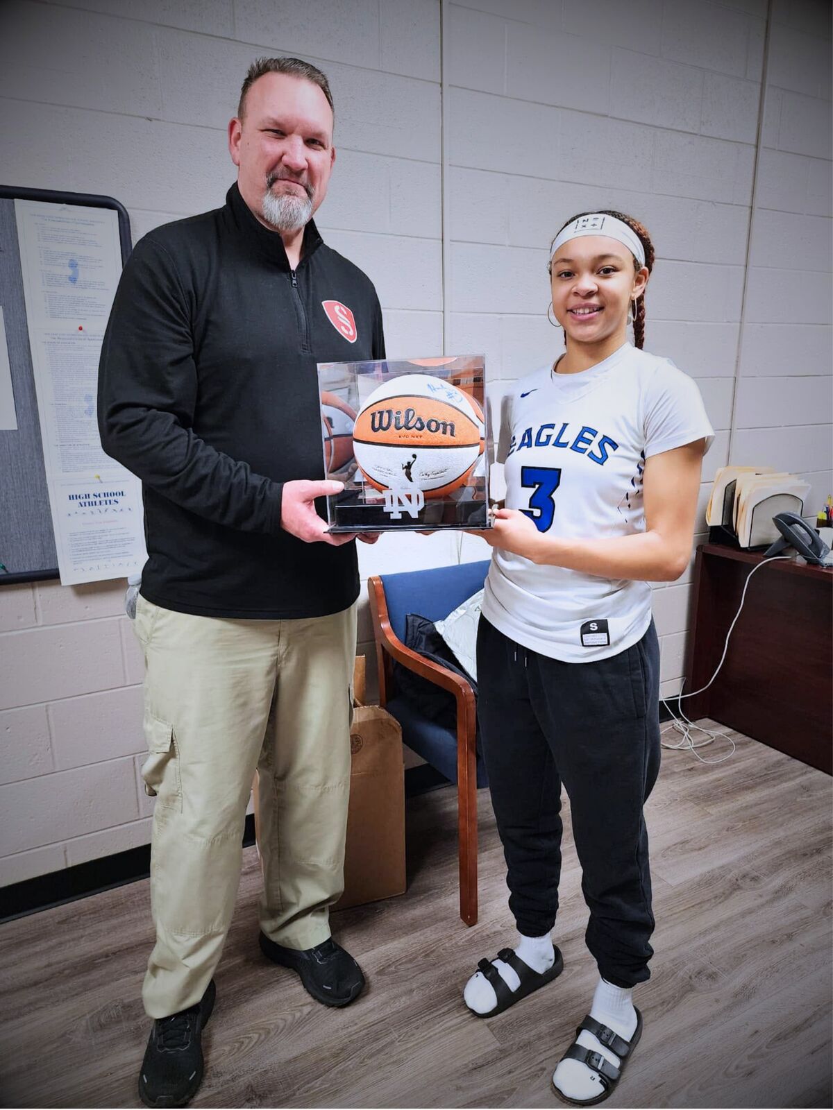 Semper Secure staff presenting a signed basketball to Notre Dame star Hannah Hidalgo